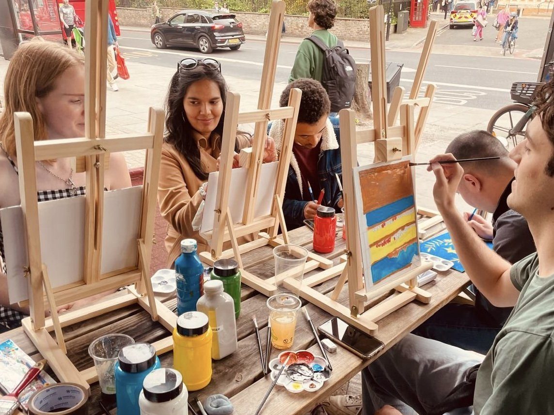 Group painting session beside a large window